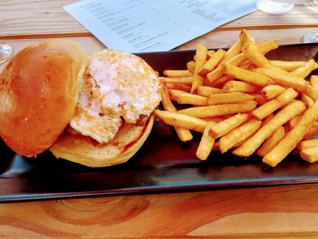 Pork Belly Sandwich with a side of fries at Faces Brewing